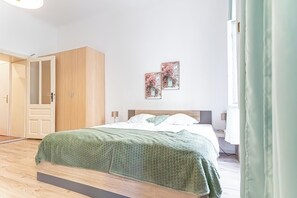 Een slaapkamer met een bed, een kledingkast en twee foto’s aan de muur.