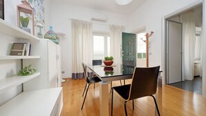 Eine moderne Küche mit einem Glastisch, Holzboden, weißen Schränken und einer grünen Tür.