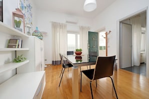 Eine moderne Küche mit einem Glastisch, Holzboden, weißen Schränken und einer grünen Tür.