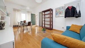 Ein modernes Wohnzimmer mit einem blauen Sofa, Holzboden und einem Essbereich mit Tisch und Stühlen.