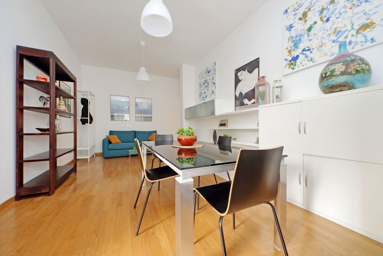 Een moderne keuken met een eettafel, stoelen en een boekenkast.