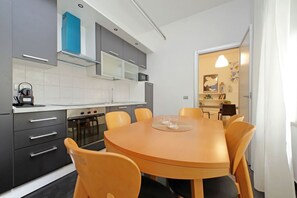 Una cocina moderna con armarios grises, una mesa redonda de madera y sillas naranjas.