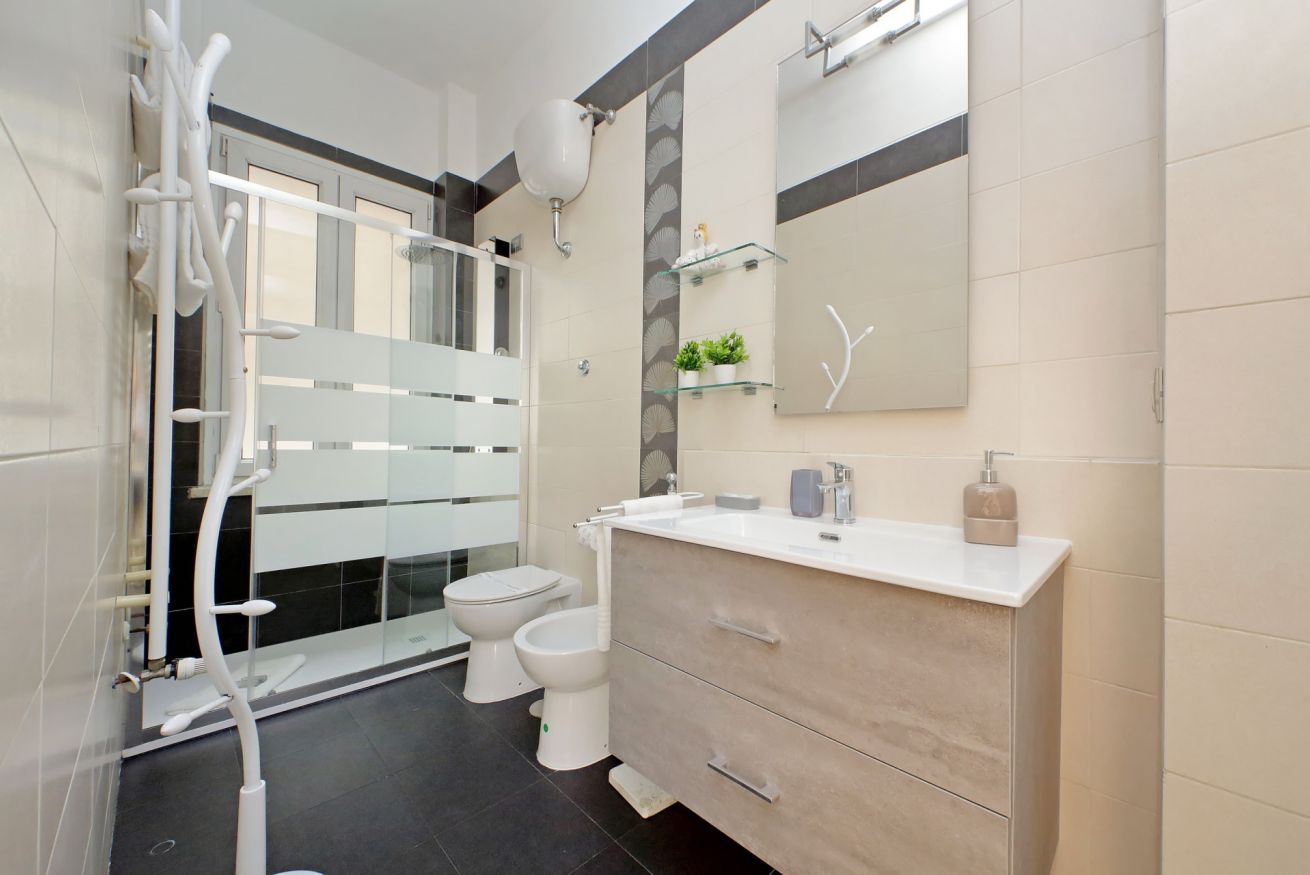 A modern bathroom with a glass shower enclosure, a toilet, and a vanity with a mirror.
