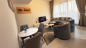 Un salon moderne avec un canapé, des fauteuils, une table basse et un téléviseur.