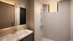 Une salle de bain moderne avec un grand miroir, un lavabo et une douche.