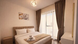 Une chambre d’hôtel comprenant un lit, une table de chevet, une commode, un miroir et une fenêtre avec des rideaux.