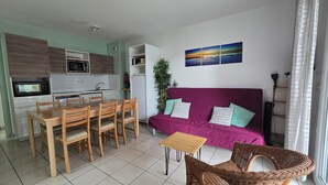 A compact living space with a dining area, kitchenette, and a sofa with cushions. - 300 m from beach. Comfort, terrace, wifi, bed linen, garden, swimming pool, parking lot (Moliets-et-Maa)
