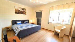 Ein Schlafzimmer mit Bett, Nachttisch, Fernseher und einem Sessel.