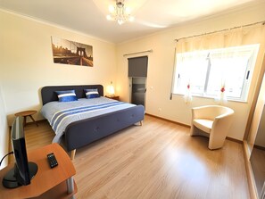 Ein Schlafzimmer mit Bett, Nachttisch, Fernseher und einem Sessel.