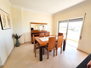 A dining area with a wooden table and chairs, a vase with dried plants, and a large mirror on the wall. - Muscari Apartment, Portimão, Algarve (Portimão)