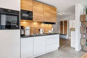 A modern kitchen with a built-in oven, microwave, and coffee maker. - Friesentraum Vacation Apartment in Greetsiel—New Construction with a Terrace (Greetsiel)