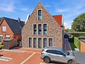 Ein zweistöckiges Haus mit geneigtem Dach, einem Auto auf der Auffahrt und einem gepflegten Garten.