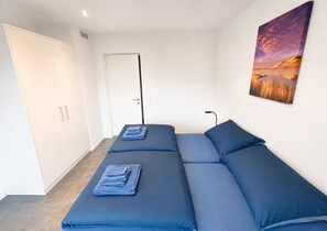 Ein moderner Raum mit Schlafsofa, einer Tür, einem Gemälde und einer Lampe.