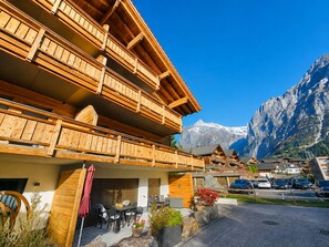 Eine Holzhütte mit Balkonen, einem Parkplatz und einem Berg im Hintergrund.