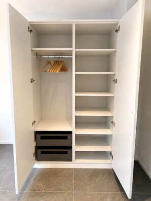 Un dressing avec plusieurs étagères et une tringle pour suspendre les vêtements.