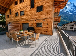 Eine Holzhütte mit Essbereich, Grillplatz im Freien und Blick auf die Berge.