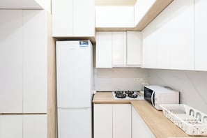 Eine moderne Küche mit weißen Schränken, einer eingebauten Mikrowelle, einem Gasherd und einem weißen Kühlschrank.