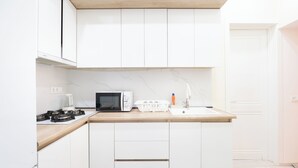 A modern kitchen with white cabinets, a microwave, a toaster, and a sink. - Tbilisi 1BR Apartment Near Fabrika (Tbilisi)