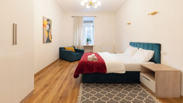A bedroom with a bed, bedside table, and a window with curtains. - Tbilisi 1BR Apartment Near Fabrika (Tbilisi)