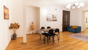 A dining area with a wooden table and chairs, a vase of dried plants, and a painting on the wall. - Tbilisi 1BR Apartment Near Fabrika (Tbilisi)