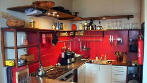Cocina compacta con estufa a gas, pileta y diferentes utensilios.