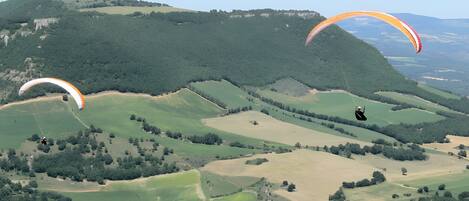 A landscape with rolling hills and two paragliders.