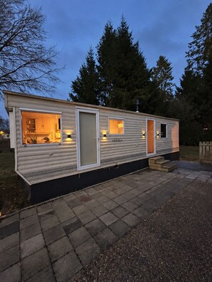 A mobile home with a kitchen area, a door, and a small window. - Boslodge 't Wims, a lovely chalet with a covered patio (Eext)