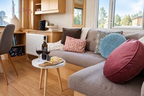 A cozy living room with a sofa, a small table with snacks and drinks, and a view of the outdoors. - Boslodge 't Wims, a lovely chalet with a covered patio (Eext)