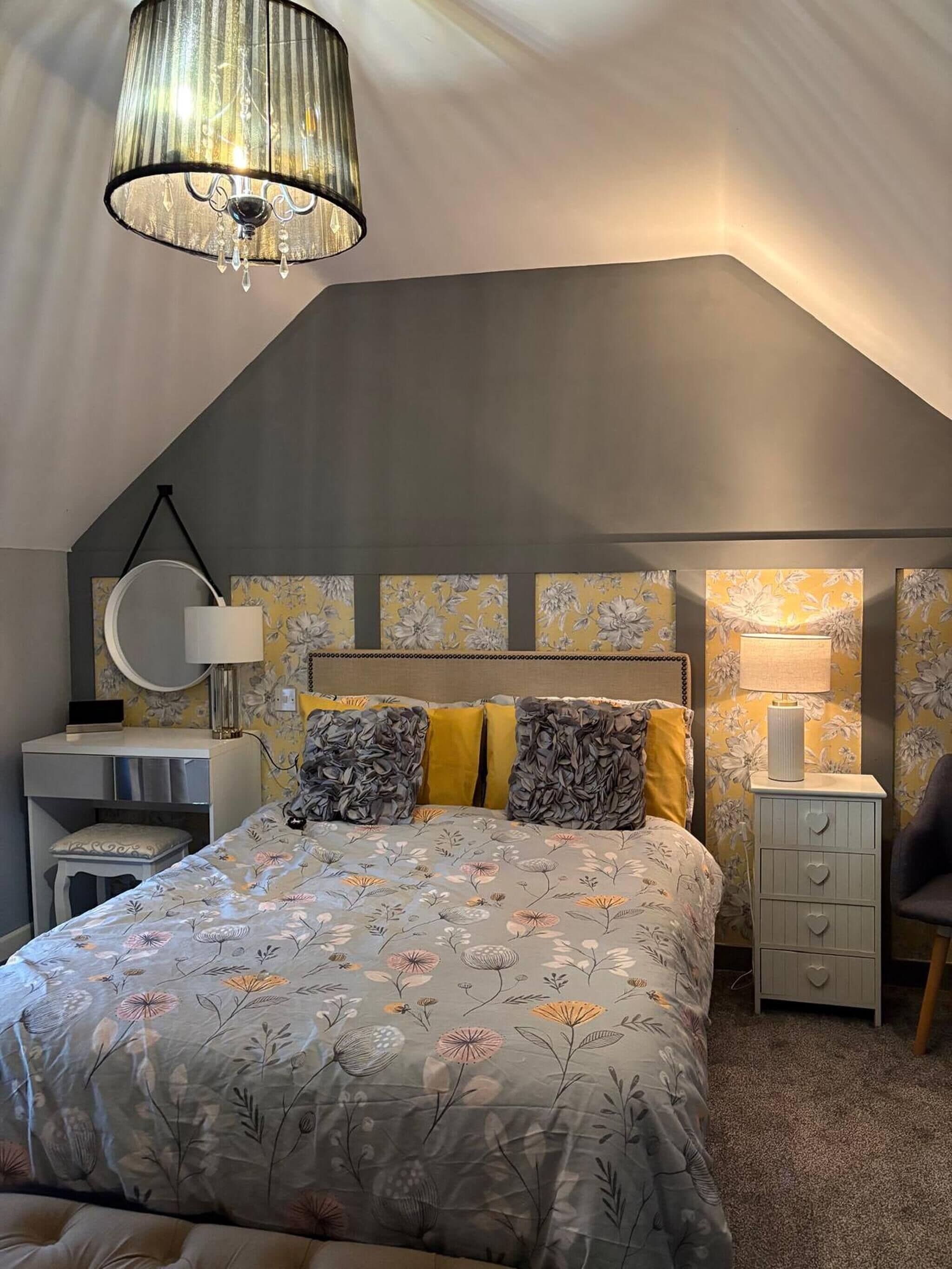 Ein Schlafzimmer mit Bett, Nachttischen, Schreibtisch, Stuhl und einer Pendelleuchte.