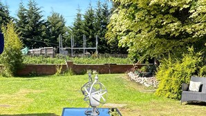 A glass-top table with two benches, surrounded by grass and trees. - The Barn at The Flute - Mill Meece (Stafford)