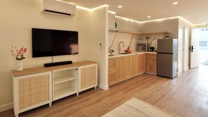 A modern kitchen with wooden cabinets, a built-in oven, and a large flat-screen TV mounted on the wall. - Alesea Suites: Surf Town Deluxe Suite 1 (San Fernando City)
