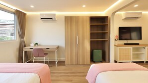 A hotel room with two beds, a desk, a chair, a wardrobe, a television, and a suitcase. - Alesea Suites: Surf Town Deluxe Suite 1 (San Fernando City)