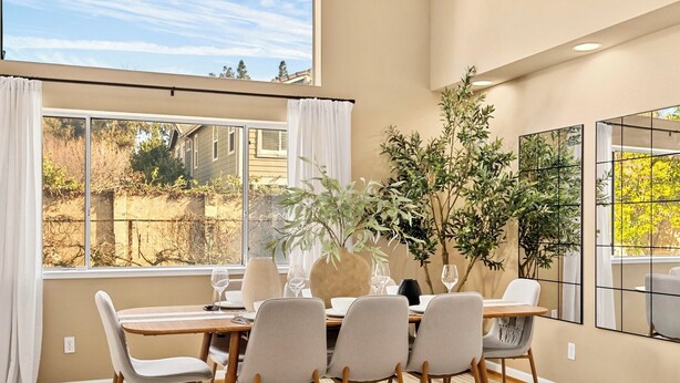 A dining area with a large window, a table set for four, and a potted plant. - Spacious and cozy home in San Jose with a park view (San Jose)