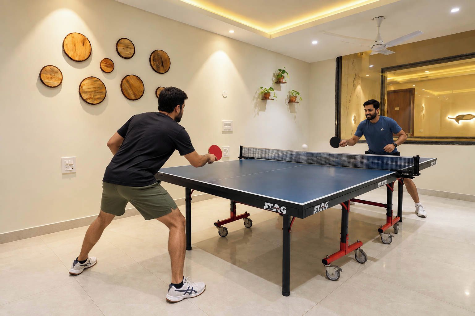 Due persone giocano a ping pong in una stanza con un tavolo da ping pong, decorazioni in legno a parete e piante in vaso.