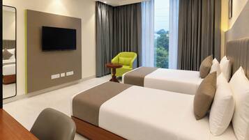 A hotel room with two beds, a TV, a chair, and a window with curtains.