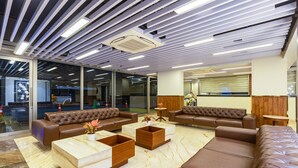 A modern interior with leather sofas, marble flooring, and a ceiling with linear lighting. - S by Z Hotels, Baani Square (Gurugram)