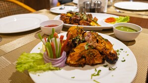 Uma mesa de jantar com pratos de comida, incluindo frango grelhado e legumes, e acompanhamentos.
