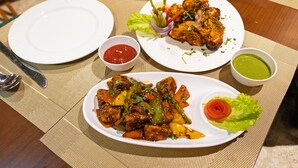 Uma mesa com três pratos de comida, duas tigelas de molho e um garfo e uma colher sobre um jogo americano.