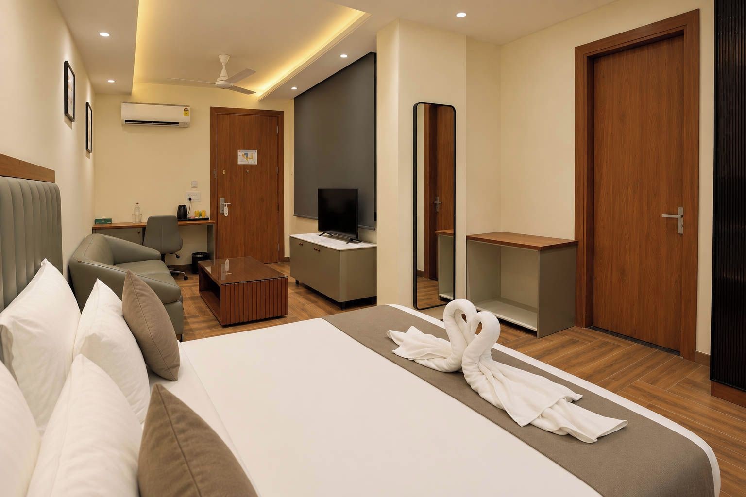A hotel room with a bed, a desk, a television, and a mirror.