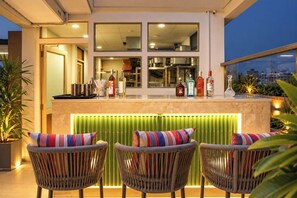 An outdoor bar area with wicker chairs and a countertop displaying various bottles. - S by Z Hotels, Baani Square (Gurugram)