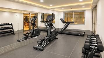 A gym with treadmills, elliptical machines, and dumbbells.