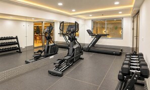 A gym with treadmills, elliptical machines, and dumbbells. - S by Z Hotels, Baani Square (Gurugram)