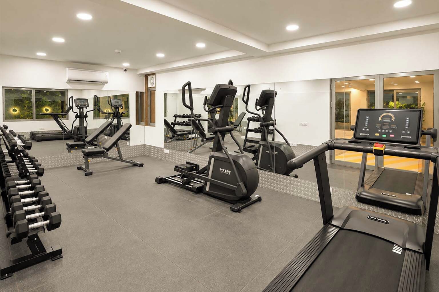 Een fitnessruimte met loopbanden, elliptische trainers en losse gewichten.