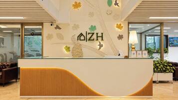 A reception desk with a modern design, featuring a wooden panel and a logo.