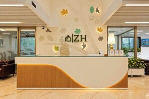 A reception desk with a modern design, featuring a wooden panel and a logo. - S by Z Hotels, Baani Square (Gurugram)