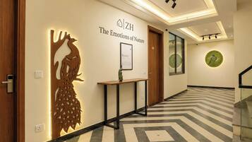 A hotel hallway with a wooden door, a wall-mounted decorative piece, a framed sign, and a patterned floor.
