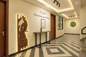 A hotel hallway with a wooden door, a wall-mounted decorative piece, a framed sign, and a patterned floor. - S by Z Hotels, Baani Square (Gurugram)