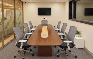 A conference room with a long table, multiple chairs, a flat-screen TV, and a potted plant. - S by Z Hotels, Baani Square (Gurugram)