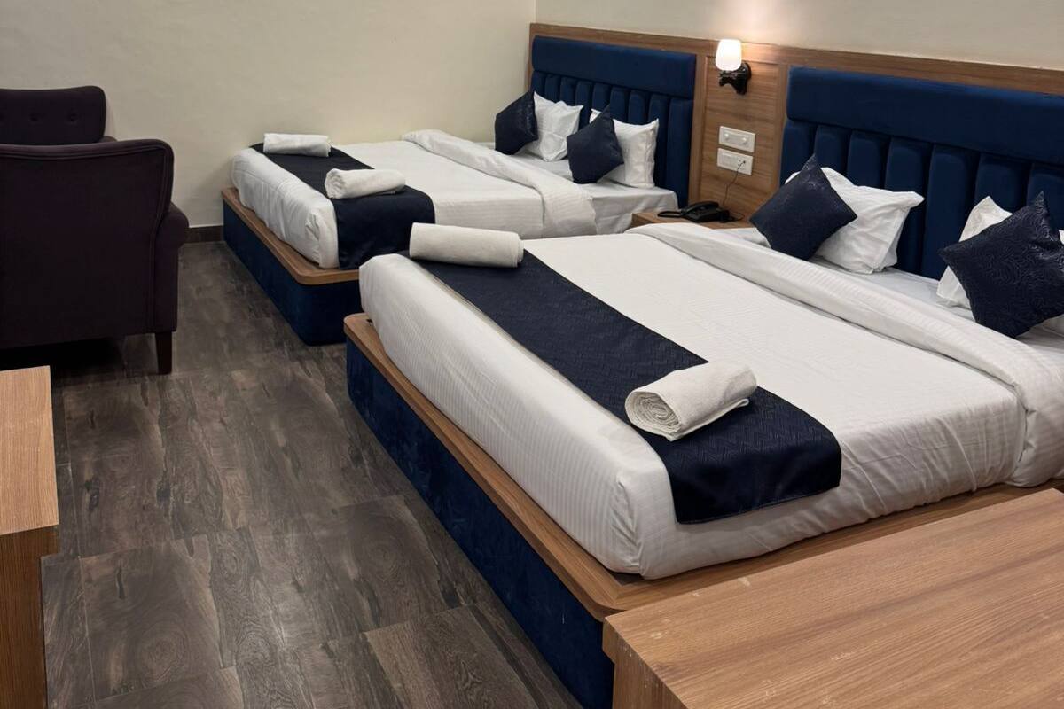 A hotel room with two beds, a desk, and a chair.