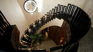 Una scala a chiocciola con finitura in legno e ringhiere nere, che conduce a un livello inferiore.